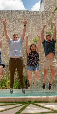 Excited winners jumping with APAC Insider award trophies against a blurred cityscape background for Erudite Tuition